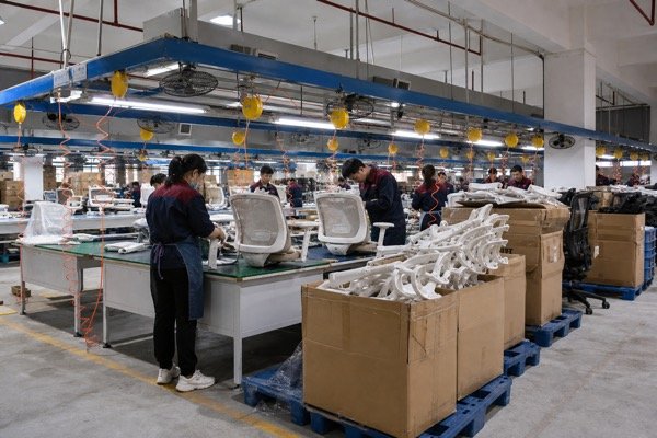 Office chair production line with workers checking chairs