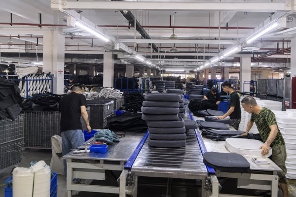 Office chair manufacturer factory production line with workers assembling chairs